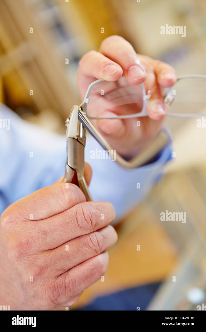 Mano de un óptico con alicates reparing gafas Foto de stock