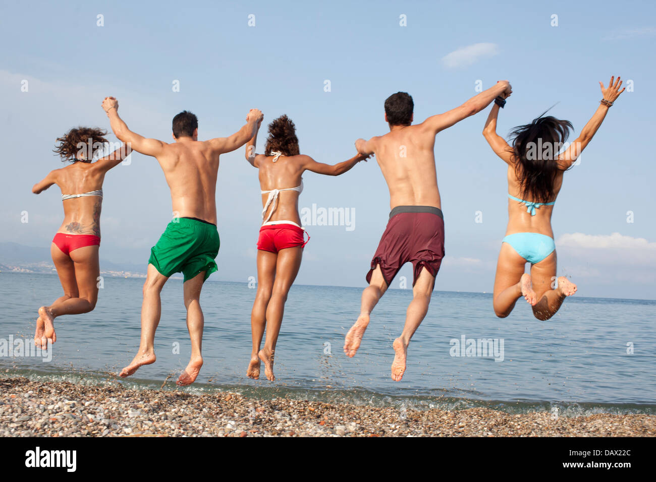 Cinco personas saltando en el mar Foto de stock