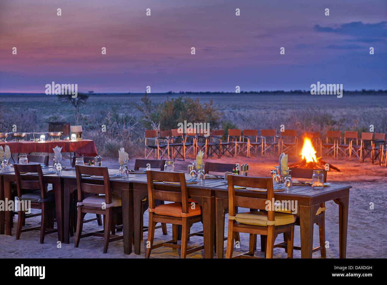 Decoradas mesa con fuego y ocaso de la Reserva de Caza del Kalahari Central, Botsuana, África Foto de stock