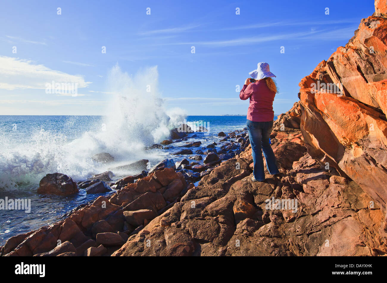 Pretty Woman tomando una fotografía de las olas rompiendo sobre las rocas de la costa rocosa en Hallett Cove Adelaida Australia del Sur Foto de stock