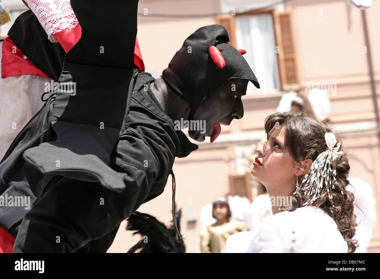 Un 'Devil' muestra a la Virgen su lengua en un desfile religioso en Campobasso, Italia, 10 de junio de 2006. Cada año los temas bíblicos y la vida de los santos son promulgadas en palanquines llevados por hombres fuertes en la procesión religiosa Misteri di Campobasso. También gente vestida como diablo generalmente niños beso en ese día. Foto: Lars Halbauer Foto de stock