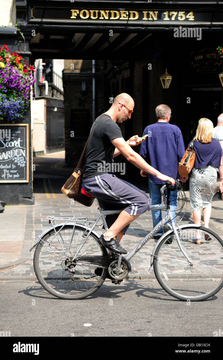 Ciclista Texting mientras viajaba en bicicleta por la Carretera.Cambridge, UK. Foto de stock