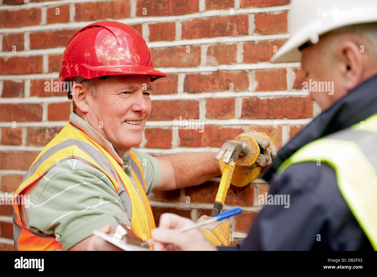 Dos trabajadores de la construcción que va sobre sus deberes. Administrador del sitio con un obrero general, tanto hablar y discutir el trabajo. Foto de stock