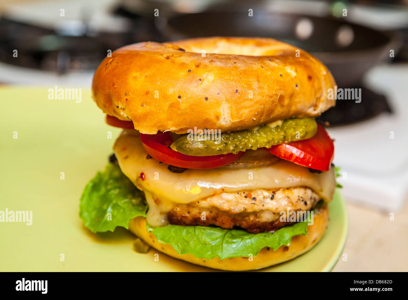 Una hamburguesa de Turquía sobre un bagel cebolla con pimienta Queso jack, pepinillos, cebollas asadas, lechuga romana, y el tomate. Foto de stock