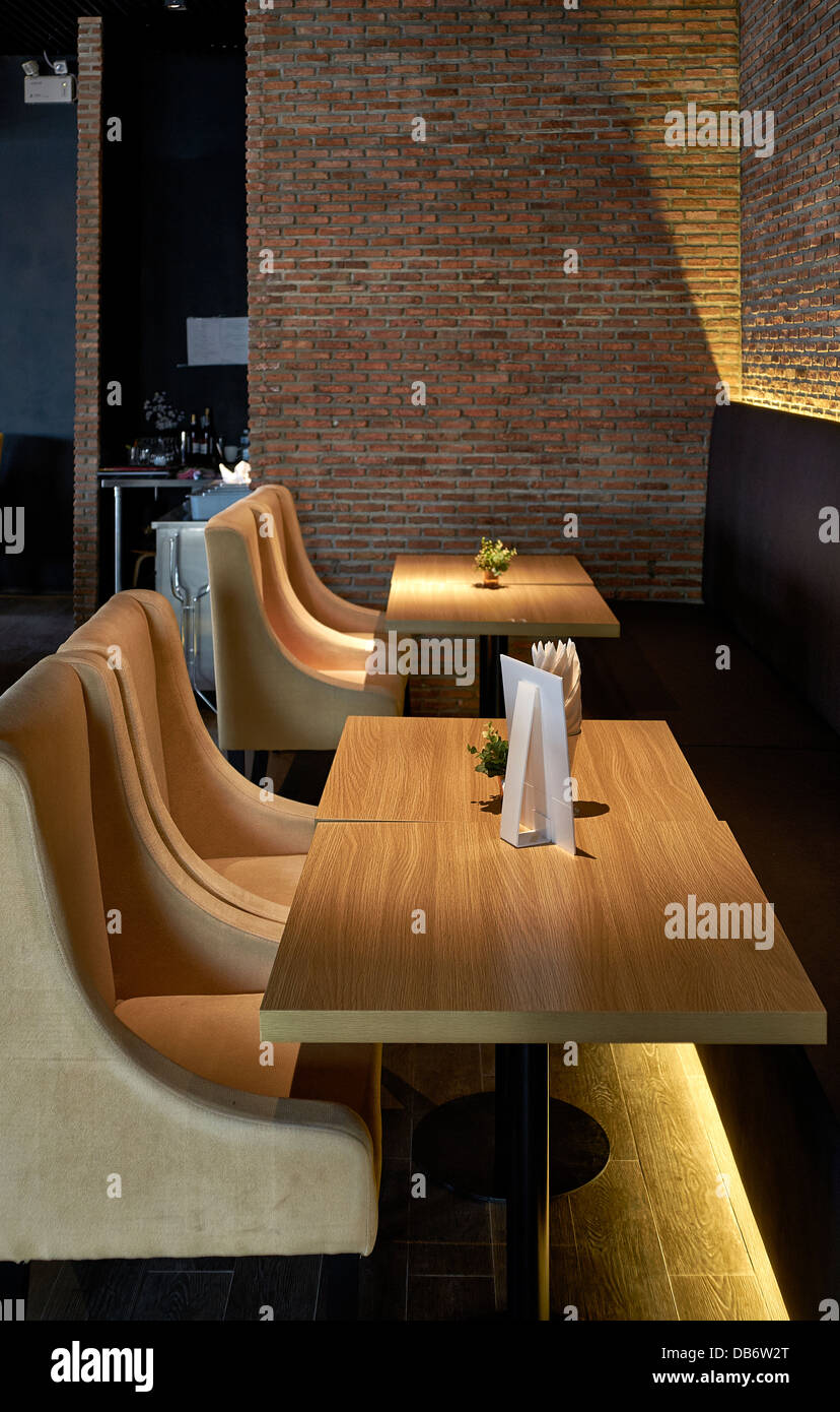 Moderno restaurante boutique con mobiliario suave e iluminación íntima con paredes de ladrillo a la vista. Foto de stock