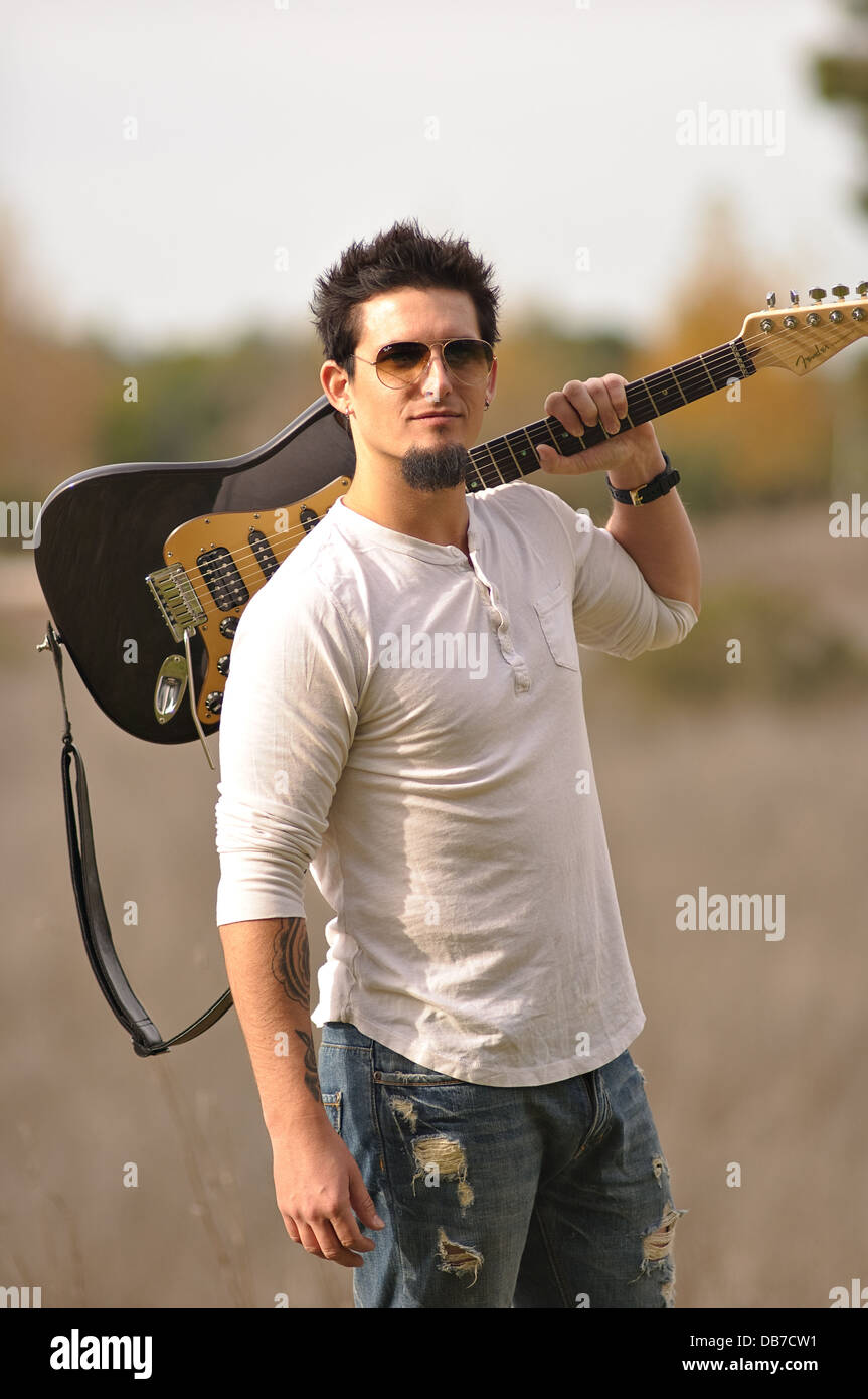 Un músico de rock con gafas de sol llevar Brown guitarra eléctrica sobre el  hombro izquierdo, posando al aire libre en la naturaleza del otoño  Fotografía de stock - Alamy