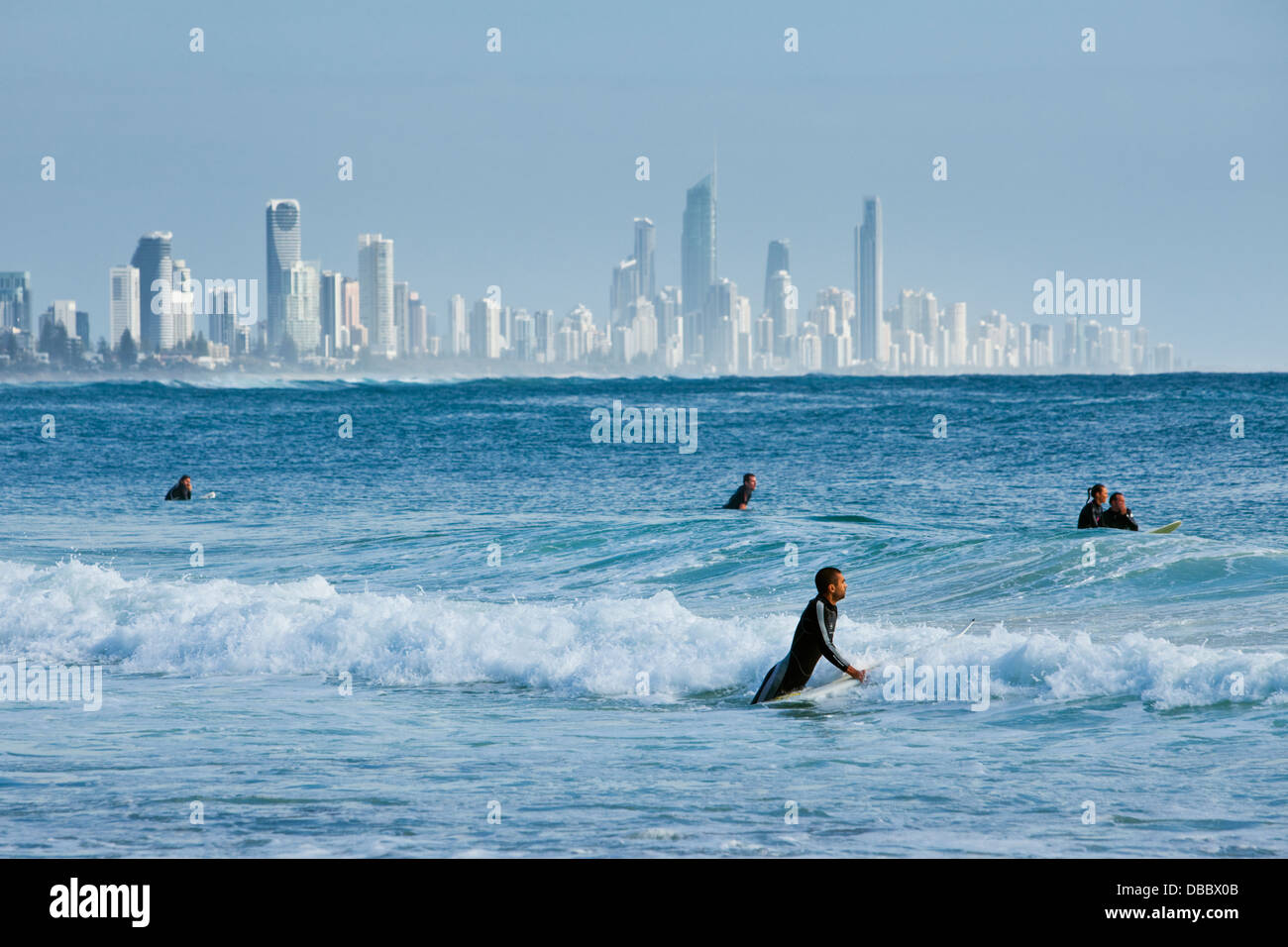 Surfistas esperando olas con vistas al horizonte de la ciudad de fondo. Burleigh Heads, Gold Coast, Queensland, Australia Foto de stock