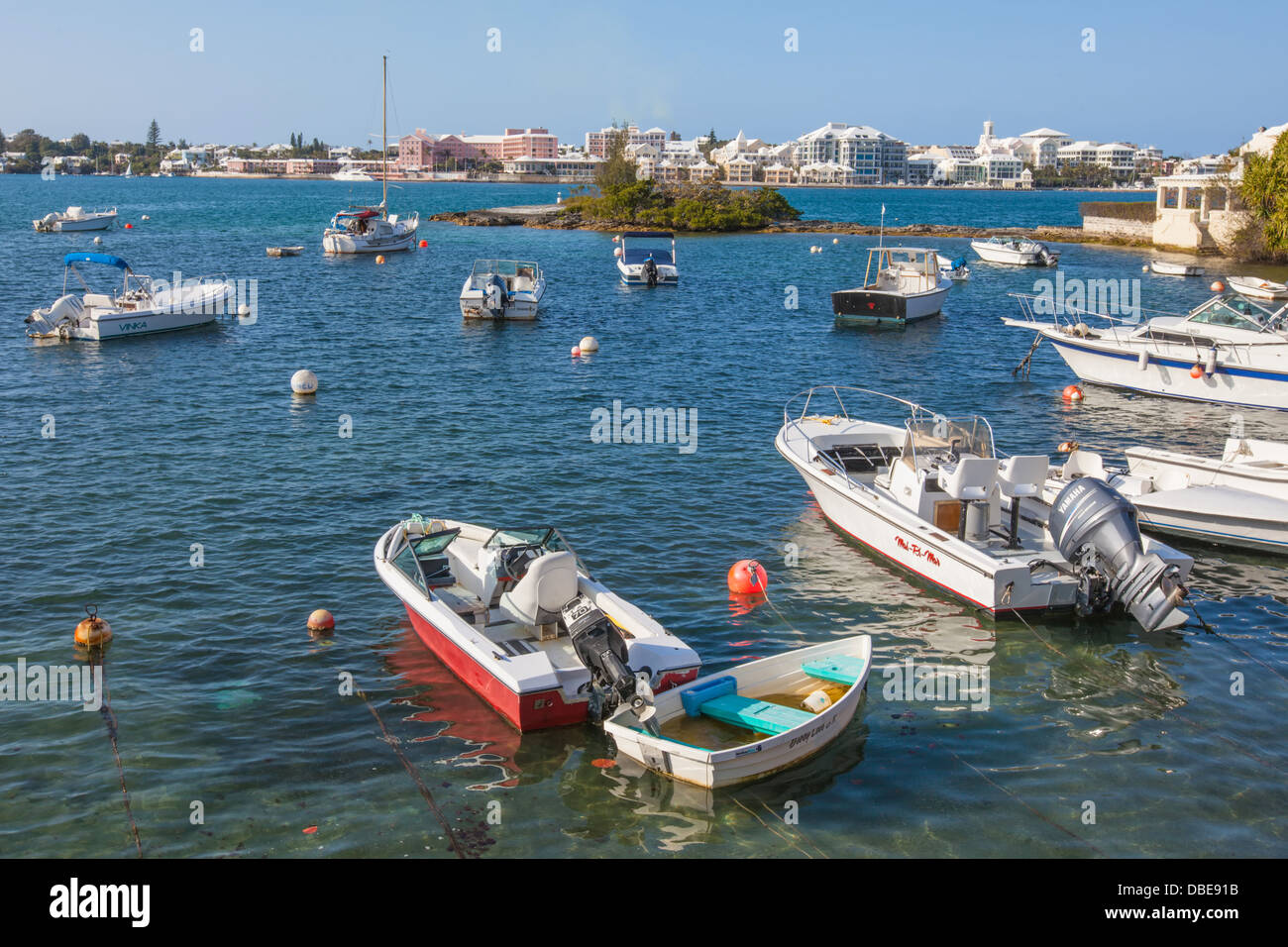 Embarcaciones de recreo amarrados a lo largo de las costas de Puerto Hamilton con la ciudad de Hamilton, Bermuda en la distancia. Foto de stock