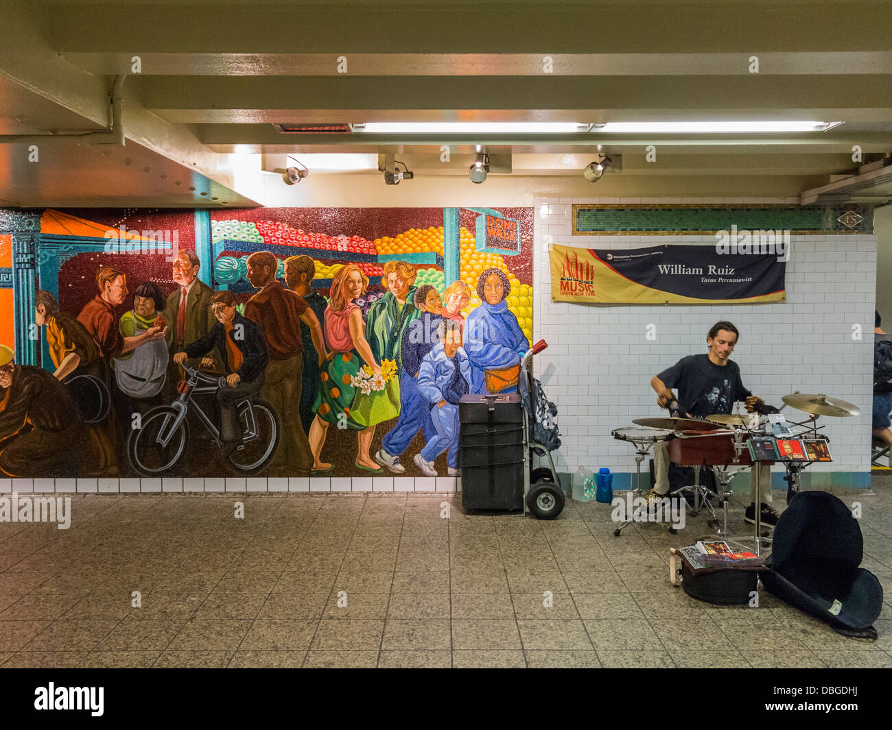 Músico callejero street ejecutante en el metro de Nueva York junto a un gran mosaicos Foto de stock