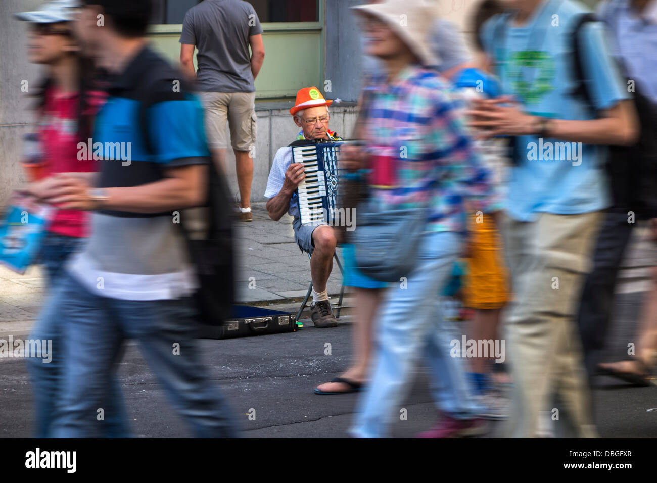 Triste escena de old man / acordeonista tocando música de acordeón inadvertido por peatones caminando en la concurrida calle comercial en la ciudad Foto de stock