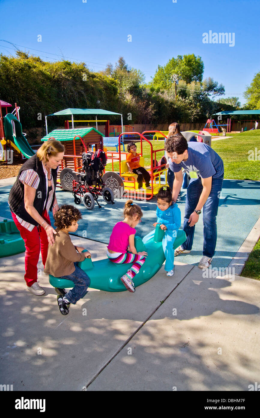 Jóvenes y viejos funcionarios ayudan los niños invidentes y discapacitados utilizar el patio en el centro de aprendizaje para niños ciegos Foto de stock
