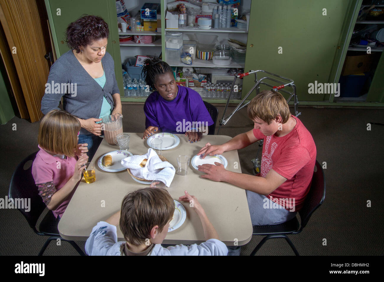 Un maestro se une a sus estudiantes ciegos y discapacitados alimentos de muestreo que hicieron en una clase de cocina y de cocción Foto de stock