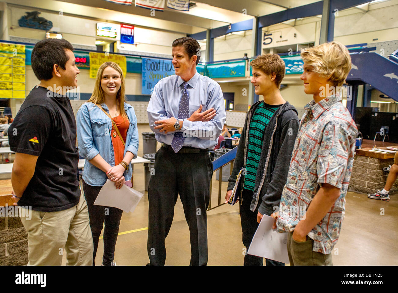 Un director de una escuela secundaria conversaciones con cuatro de sus estudiantes en el edificio de la escuela atrium en Dana Point Foto de stock