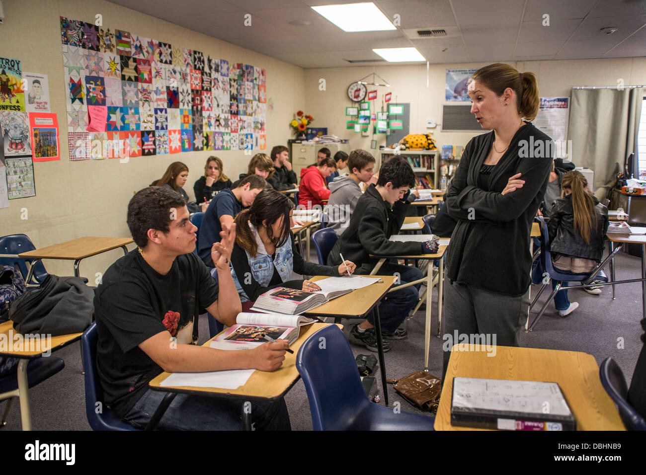 Maestro de Inglés de escuela secundaria de California ayuda a la comprensión de sus estudiantes durante un ejercicio de lectura utilizando una antología literaria Foto de stock