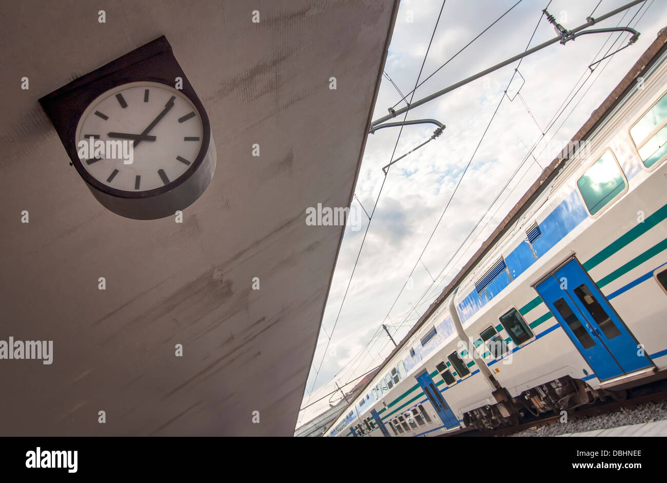 Reloj en el andén de una estación de tren con un vagón parado Foto de stock