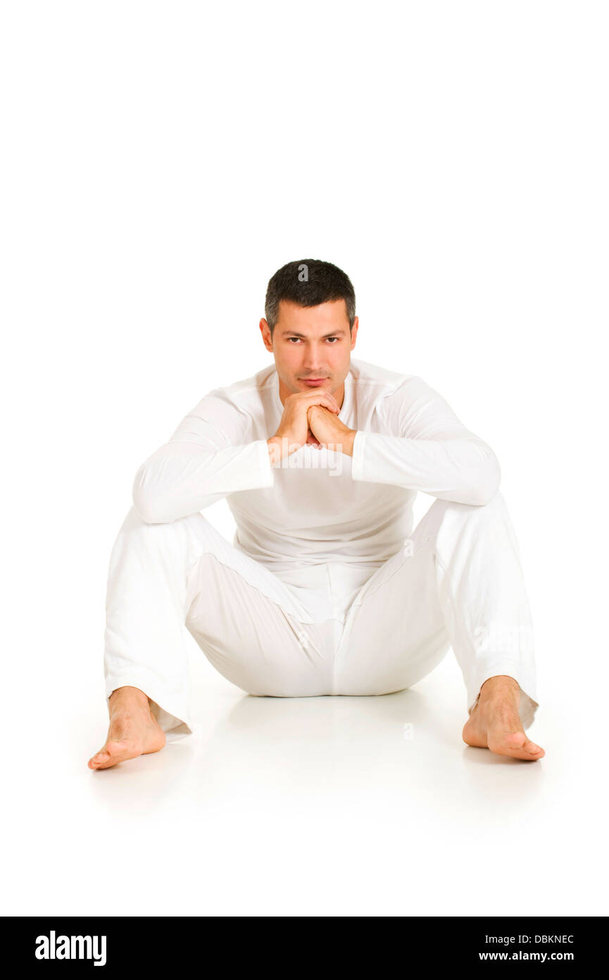 Hombre vestido de blanco sentado en el suelo Foto de stock