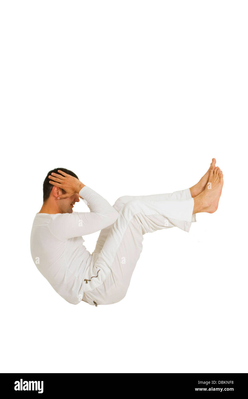 Hombre vestido de blanco, sentados en el suelo hace que el abdomen Foto de stock