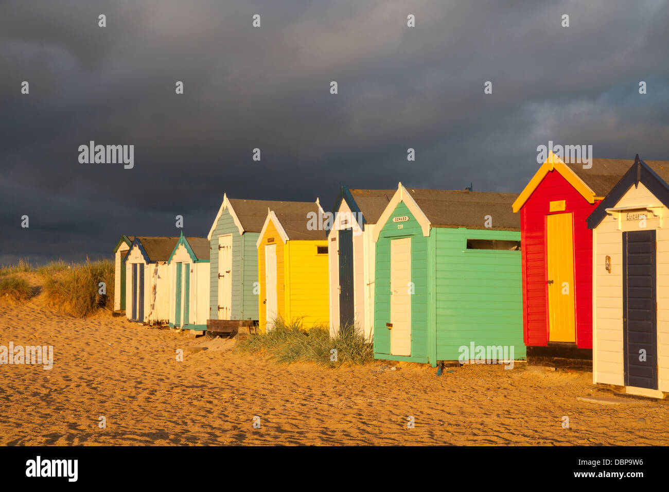 Cabañas de playa en la playa Southwold contra un cielo gris oscuro tormentoso, Suffolk, Reino Unido Foto de stock