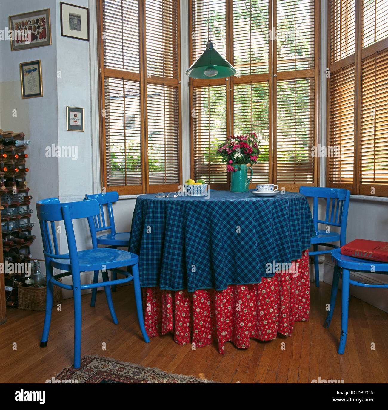 Sillas pintadas de azul brillante en la mesa con telas rojas y azules en la  parte delantera del comedor ventana con persianas de madera Fotografía de  stock - Alamy