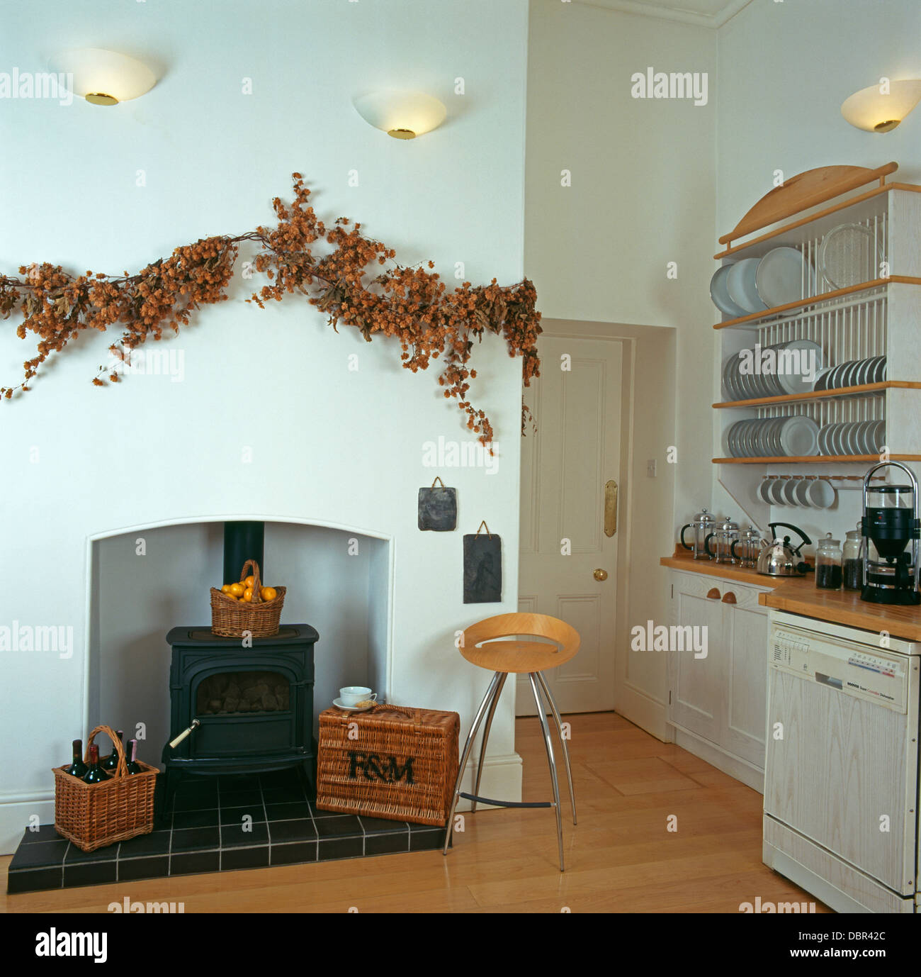 Guirnalda de flores secas más allá de una sencilla chimenea con estufa de  leña en la cocina del país blanco, con pisos de madera Fotografía de stock  - Alamy