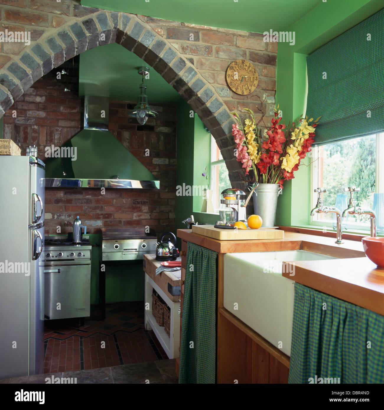 Arco de Ladrillo en la pequeña cocina verde con verde en la ventana ciega  por encima de Belfast Sink en la unidad equipada con cortinas marcada verde  Fotografía de stock - Alamy