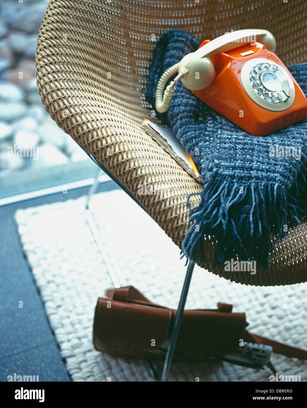 Cerca de cincuenta naranja y azul teléfono manta en 1950 estilo silla de mimbre Foto de stock