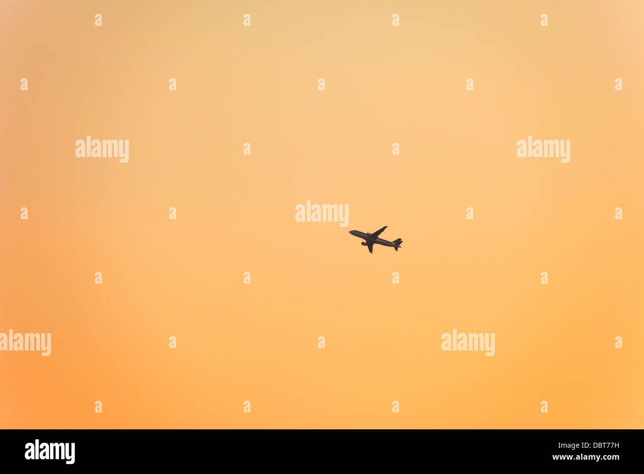 Silueta de avión en el cielo naranja Foto de stock