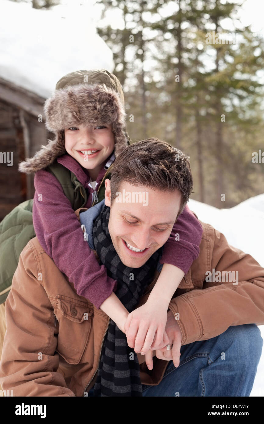 Retrato del hijo feliz abrazando a padre en la nieve Foto de stock