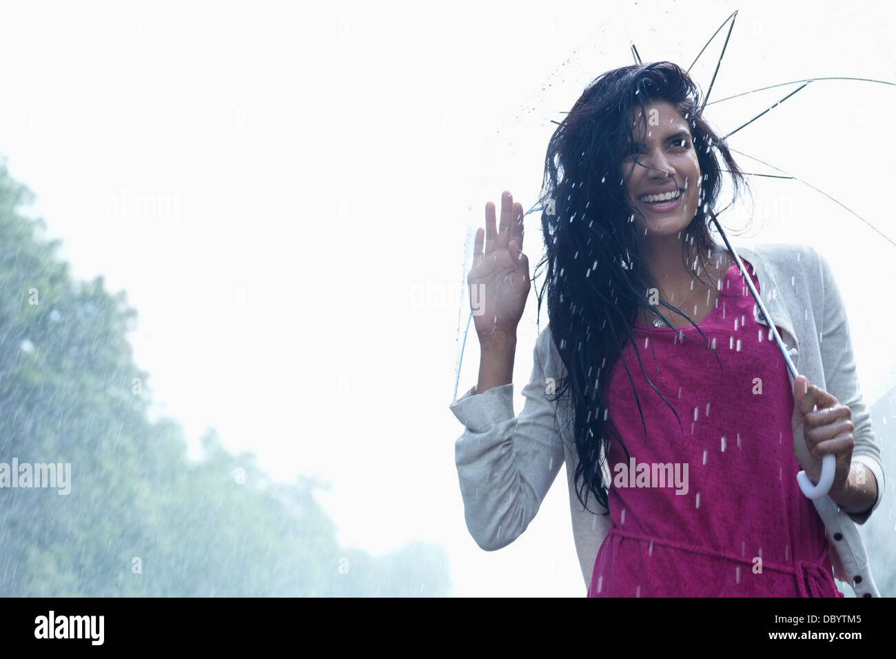 Retrato de mujer sonriente bajo el paraguas en la lluvia Foto de stock