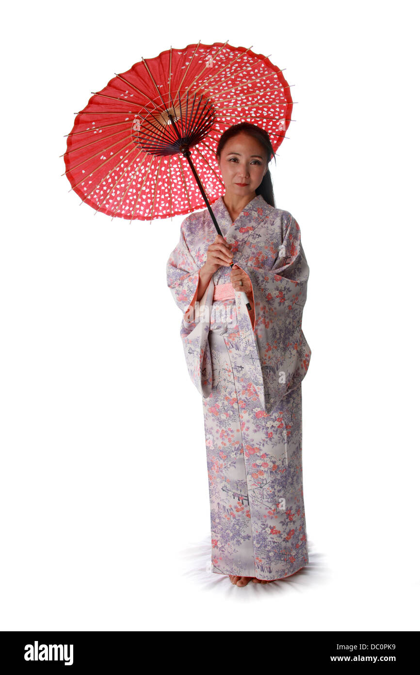 Dama japonesa vistiendo una Rosa Lila y telas de kimono rojo y sosteniendo un parasol. Foto de stock