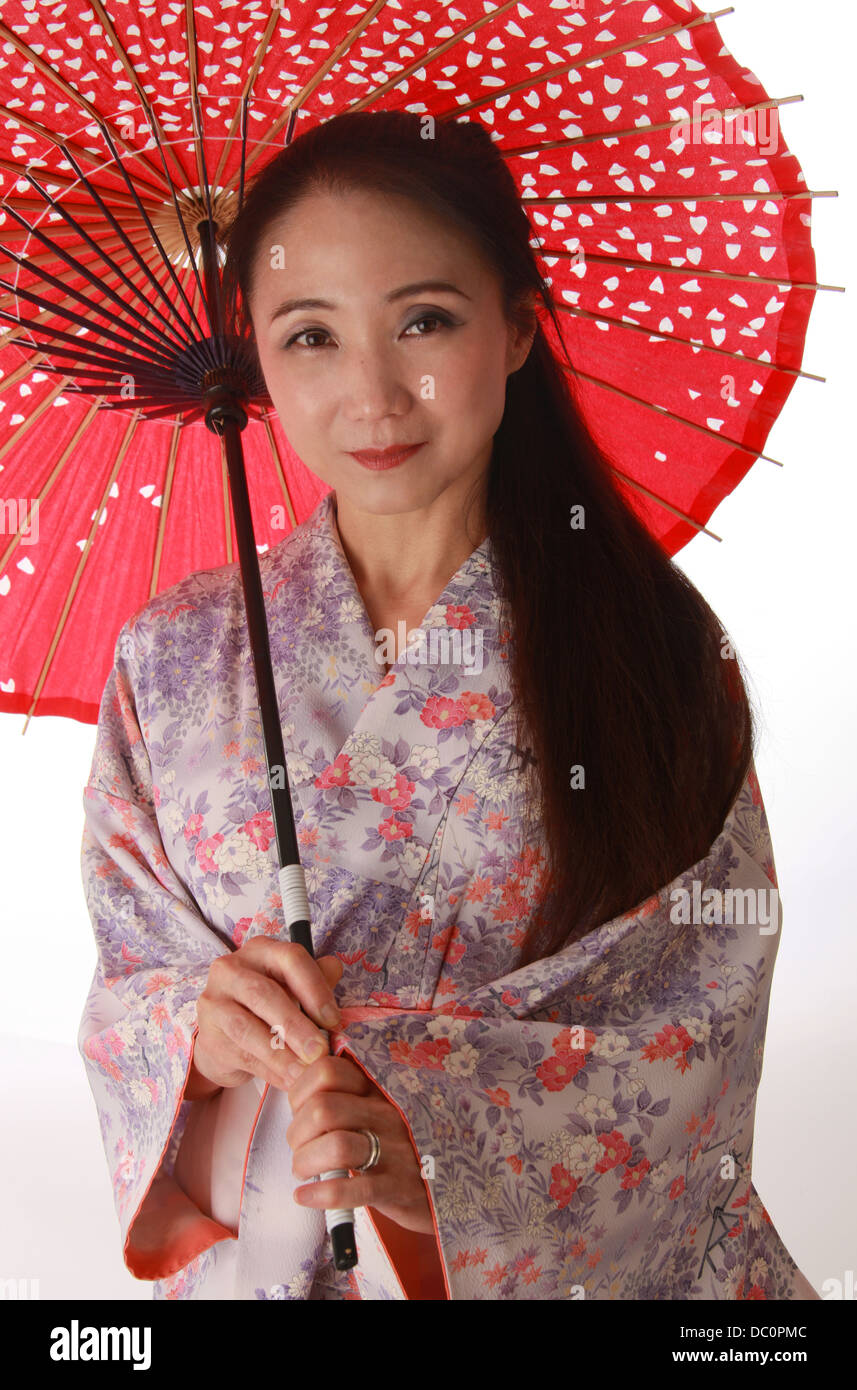 Dama japonesa vistiendo una Rosa Lila y telas de kimono rojo y sosteniendo un parasol. Foto de stock
