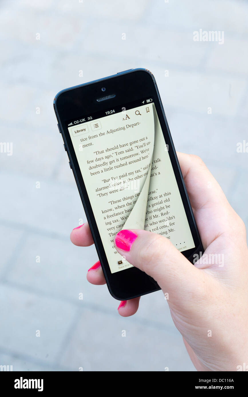 Mujer que ingresa a la página virtual de un ebook de Apple con la aplicación iBooks en el iPhone 5 Foto de stock