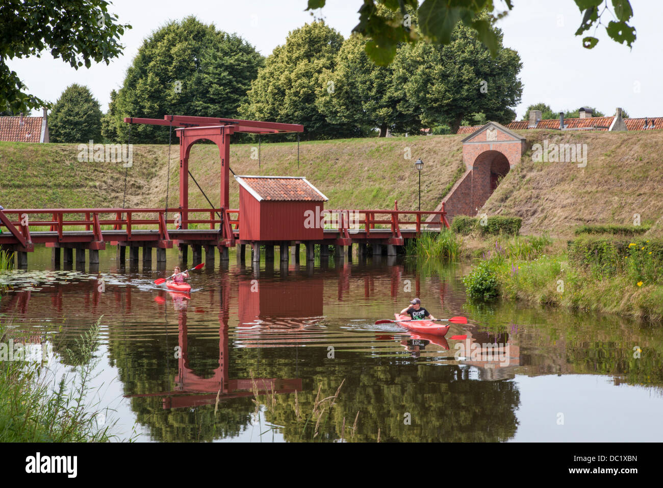 Los turistas en kayaks en kayak en el canal alrededor de la aldea de la fortaleza de Bourtange en los Países Bajos, pasando un puente levadizo Foto de stock