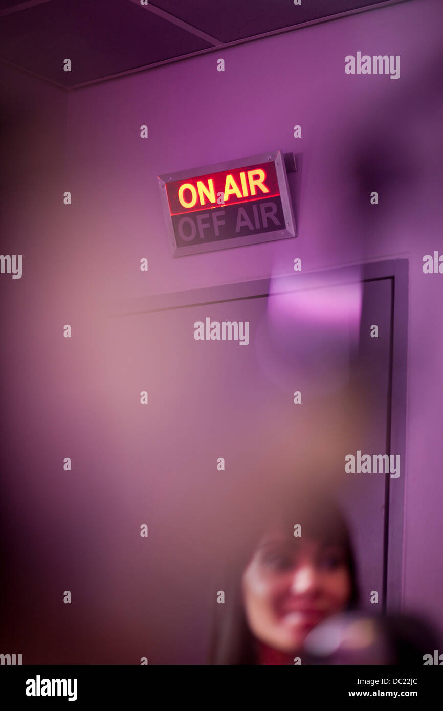 Mujer adulta media en el estudio de grabación con señal luminosa Foto de stock