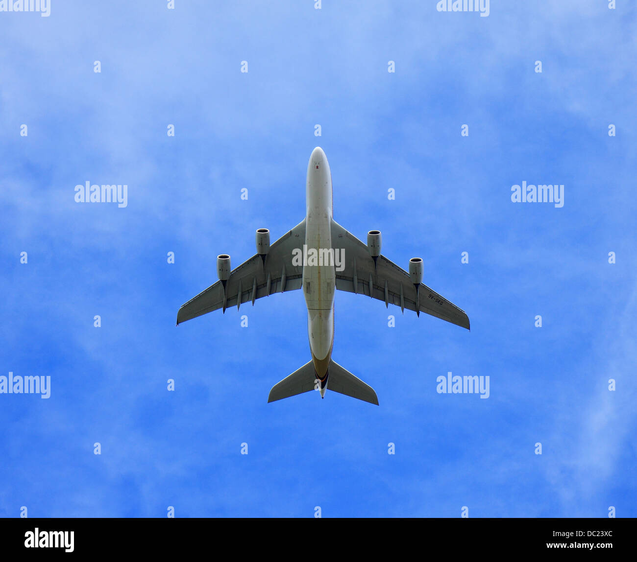 Jumbo Jet avión volando directamente encima de cielo azul y nubes cirrus Foto de stock