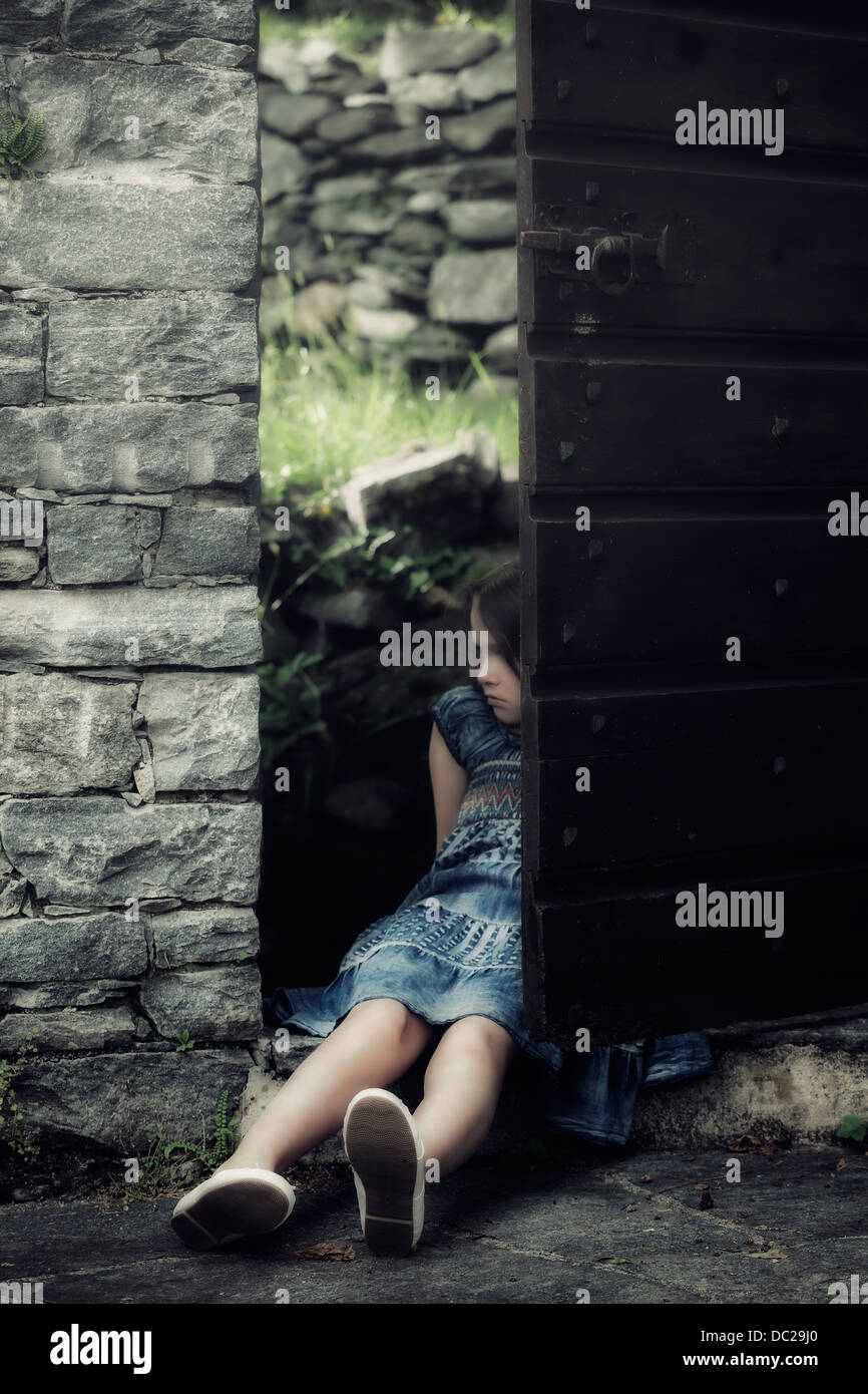 Una triste, joven está sentado en una antigua puerta Foto de stock