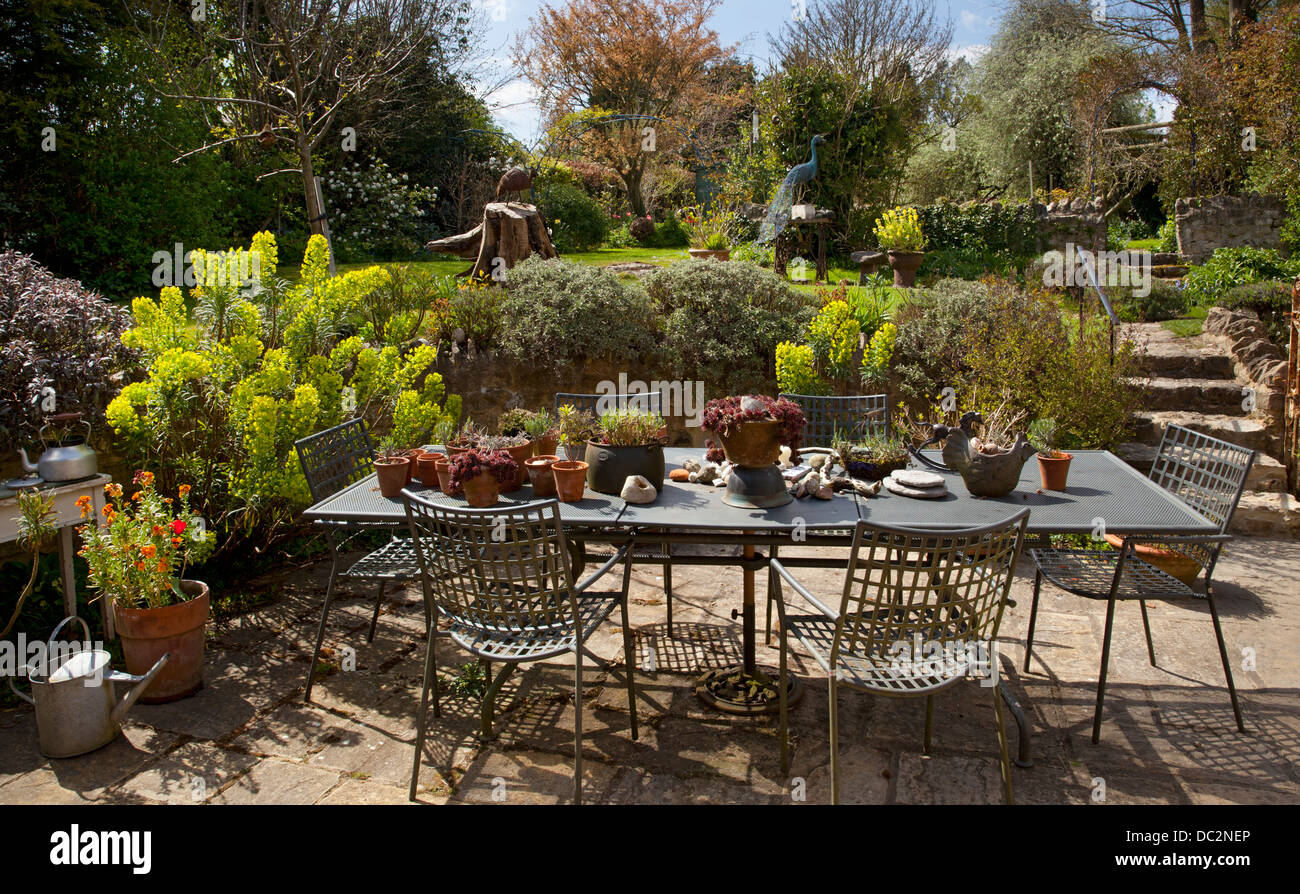 Casa rural patio jardín con muebles mesa metálica y euphorbia sembrar y plantas de maceta, Inglaterra Foto de stock