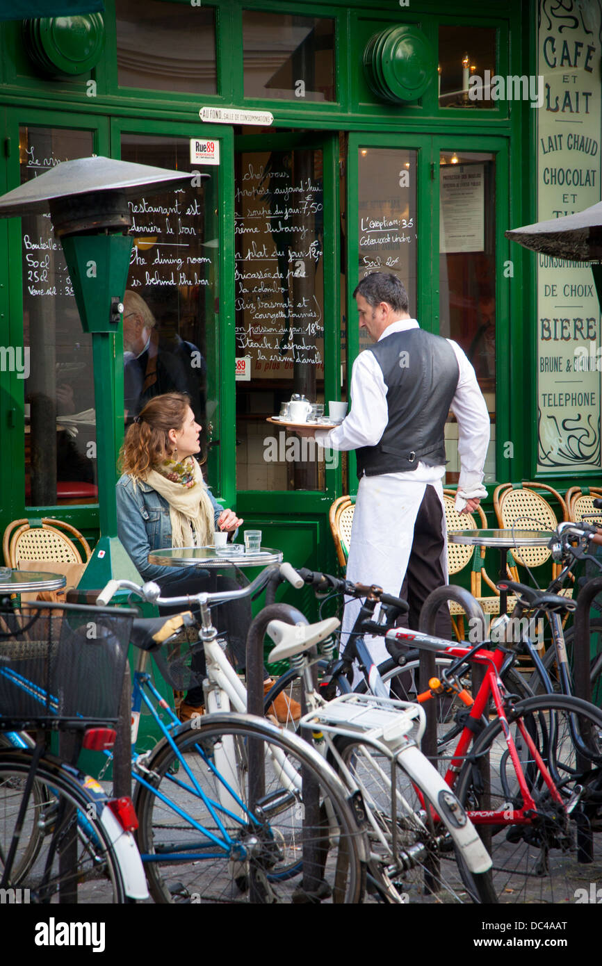 El camarero y el cliente en una cafetería en les Marais, París Francia Foto de stock