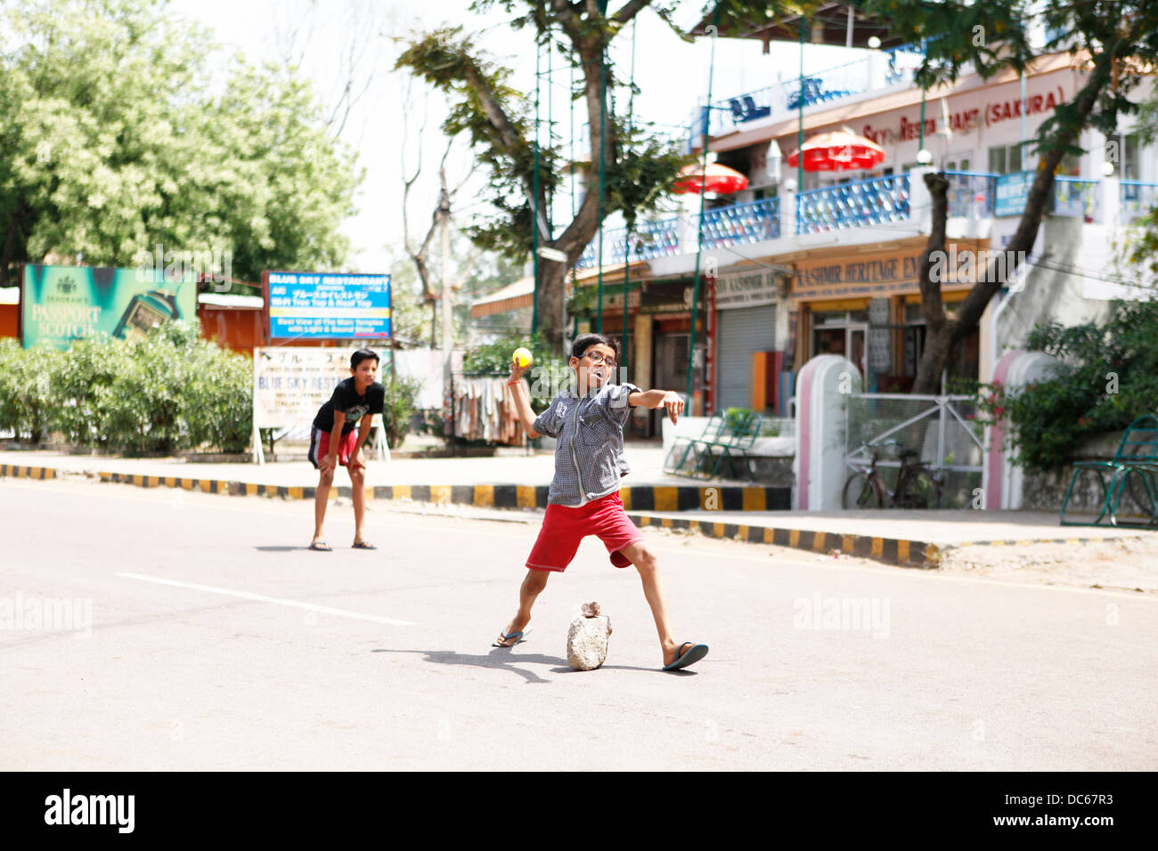Un joven jugador muestra verdadero entusiasmo como él tazones una pelota durante un juego de cricket de calle en Khajuraho, India Foto de stock