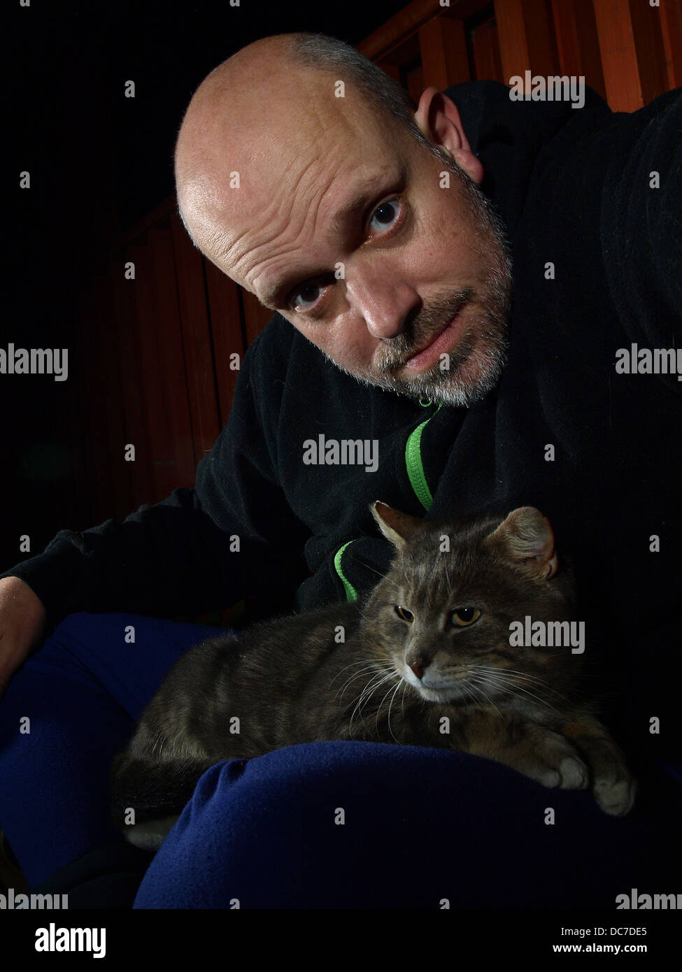 Hombre y gato con fondo oscuro Foto de stock