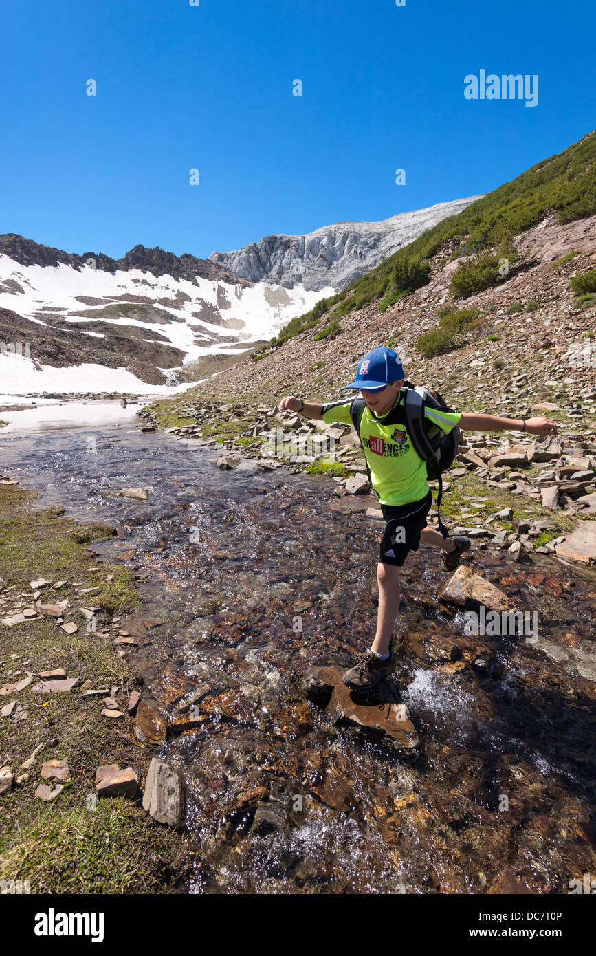 Boy cruzar una corriente alta en las montañas Wallowa de Oregon. Foto de stock