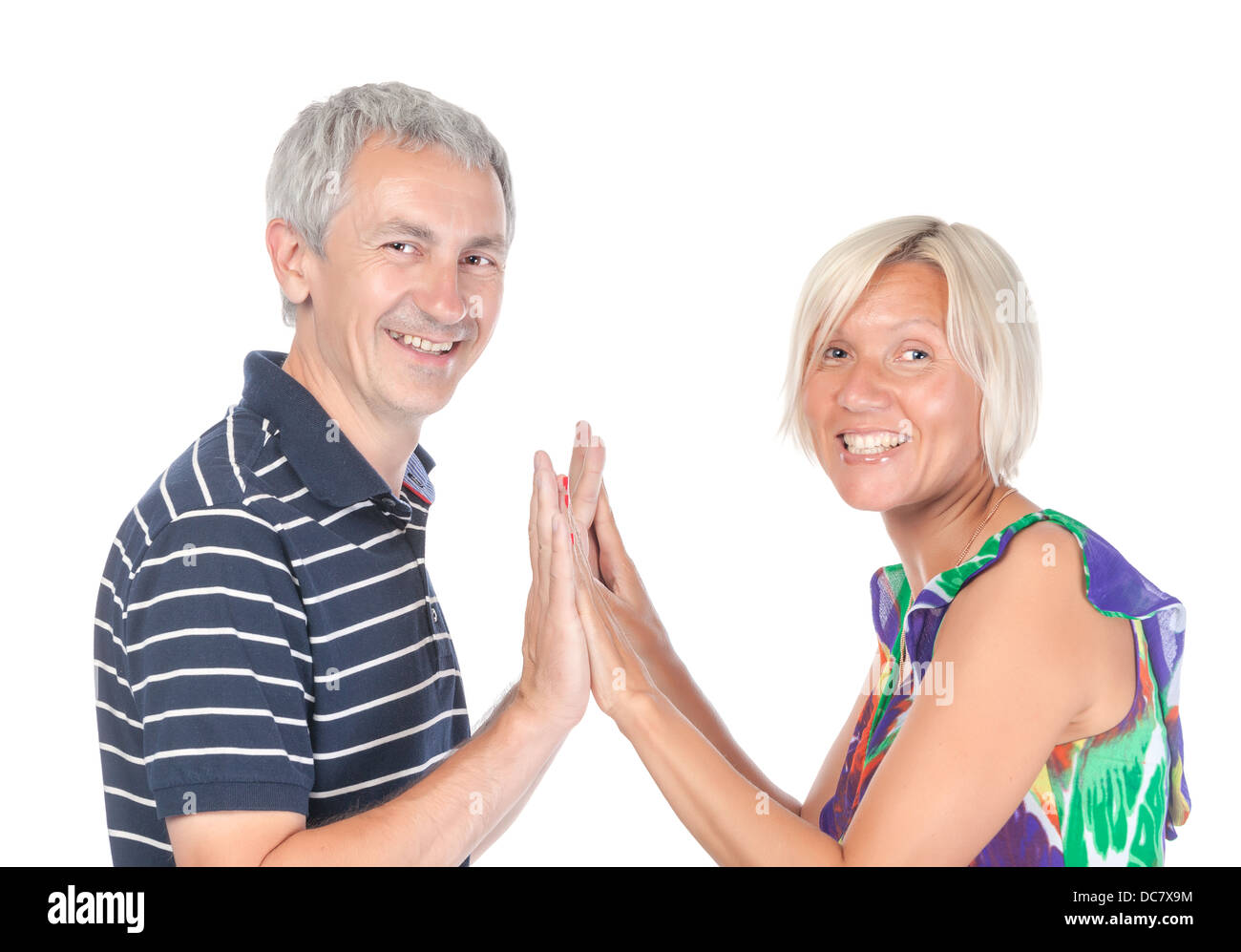 Feliz atractivo de mediana edad hombre y mujer de pie con sus palmas unidas volviendo a sonreír a la cámara Foto de stock