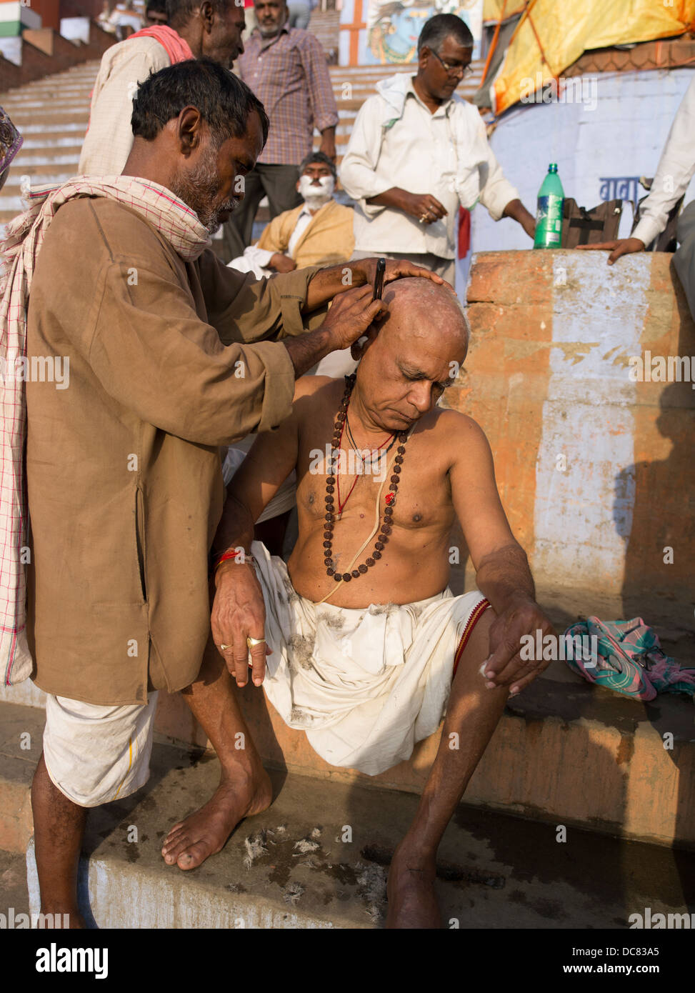 Afeitado matutino. Corte de pelo. La vida en las orillas del río Ganges - Varanasi, India Foto de stock