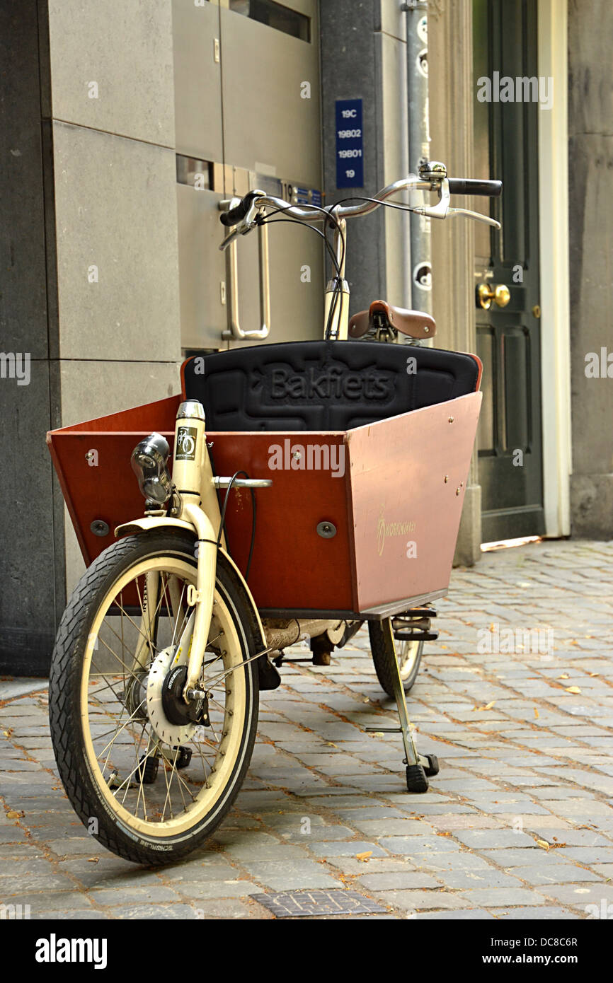 Entrega vieja bicicleta (bakfiets) en frente de la tienda en la Onze Lieve Vrouw Plein en Maastricht en el casco antiguo de la ciudad. Foto de stock