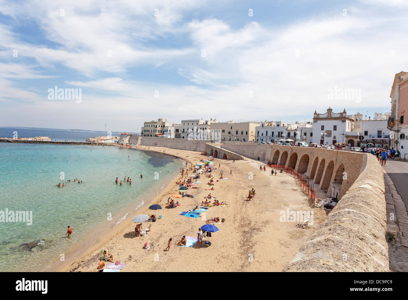 Playa de arena con coloridas sombrillas en un día soleado de verano en el centro histórico de Gallipoli, Apulia, en el sur de Italia Foto de stock