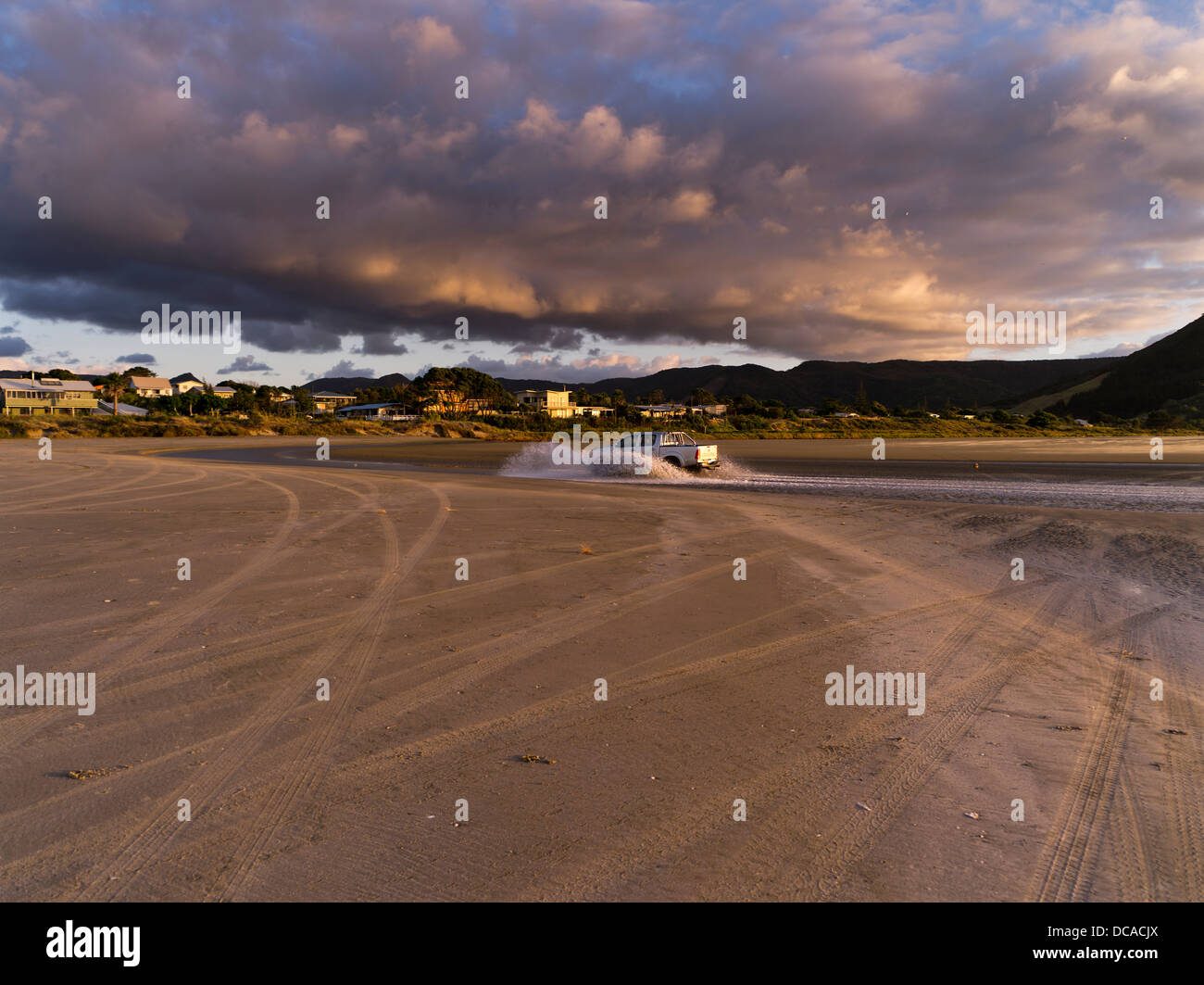 Dh 90 Mile Beach AHIPARA NUEVA ZELANDIA La conducción de automóviles en el río de la playa por la noche la luz del anochecer northland Foto de stock