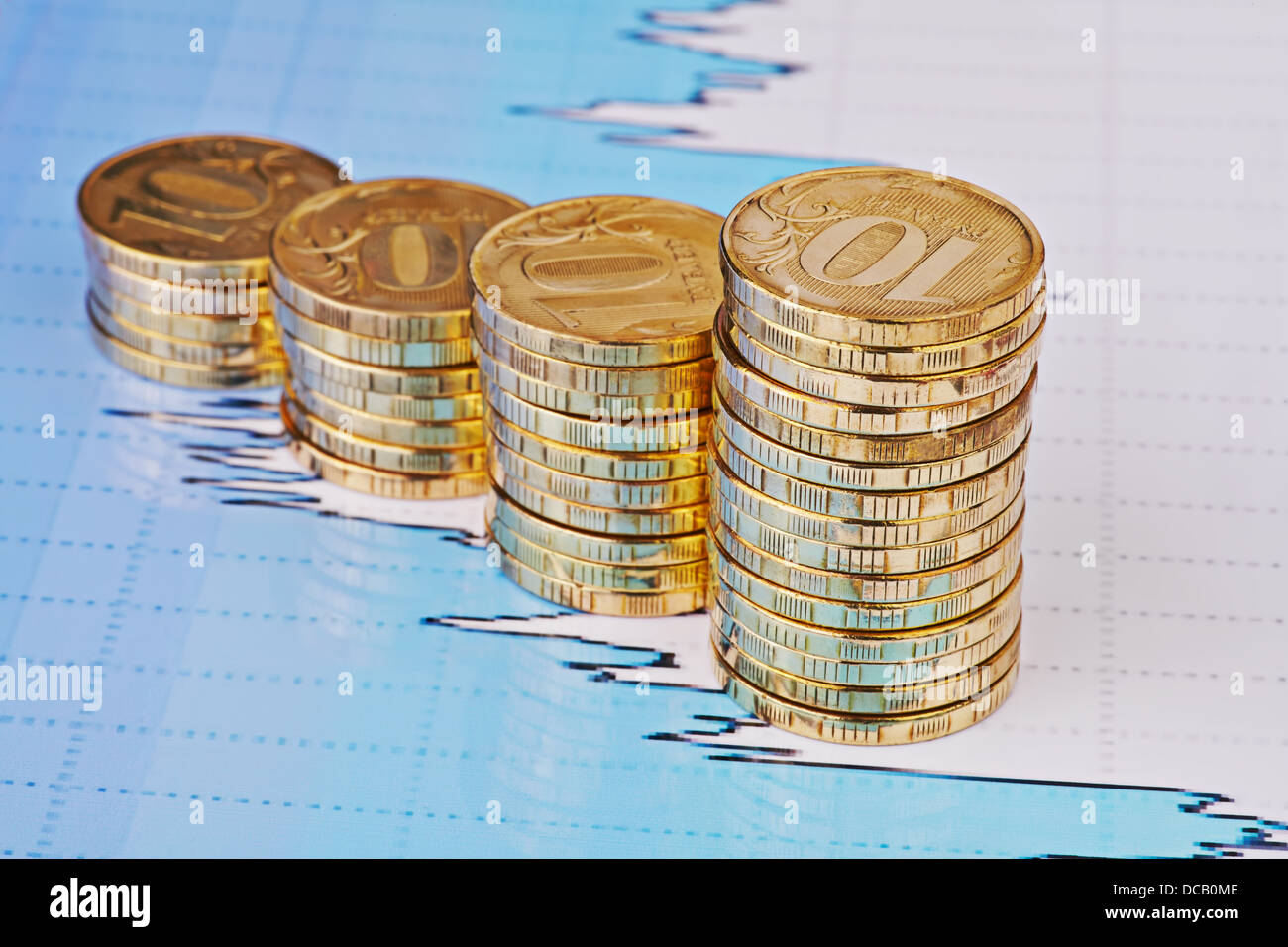 Subida apila monedas,en los gráficos de cotizaciones financieras como fondo. Enfoque selectivo Foto de stock