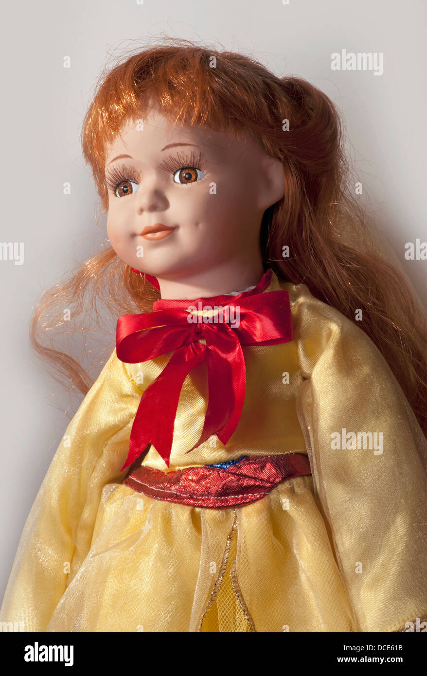 Cara de muñeca con bonito vestido amarillo, ojos marrones y pelo rojo Foto de stock