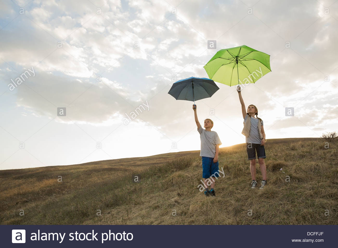 Los niños sosteniendo paraguas hasta el cielo Foto de stock