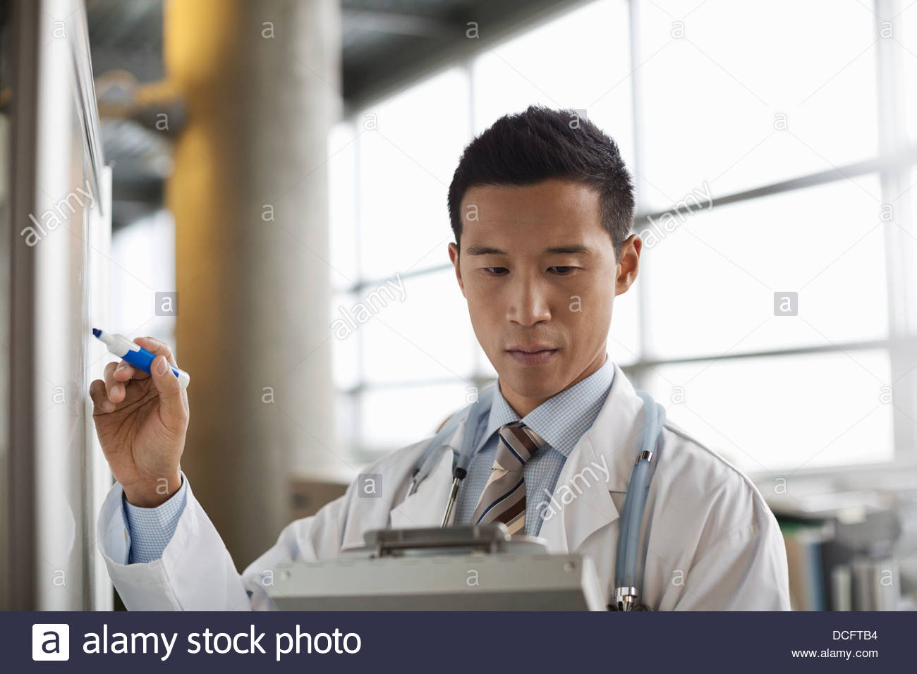 Médico varón copiando notas desde el portapapeles Foto de stock